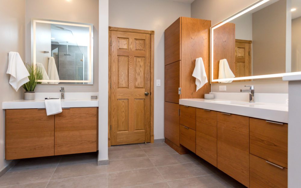 A bathroom with wood cabinetry and mirrors with lights 