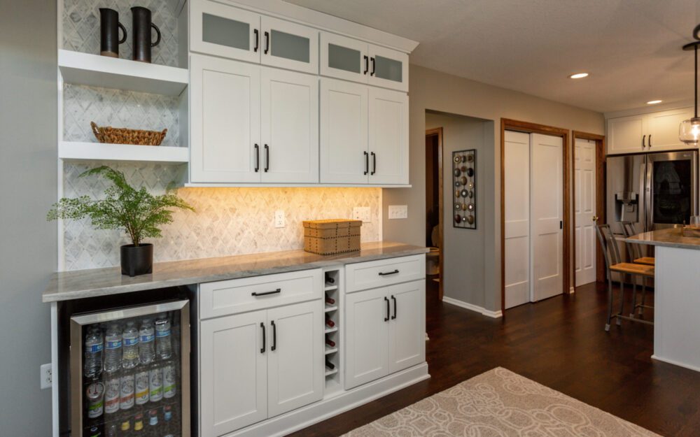 White cabinetry and a small refrigerator for refreshments  