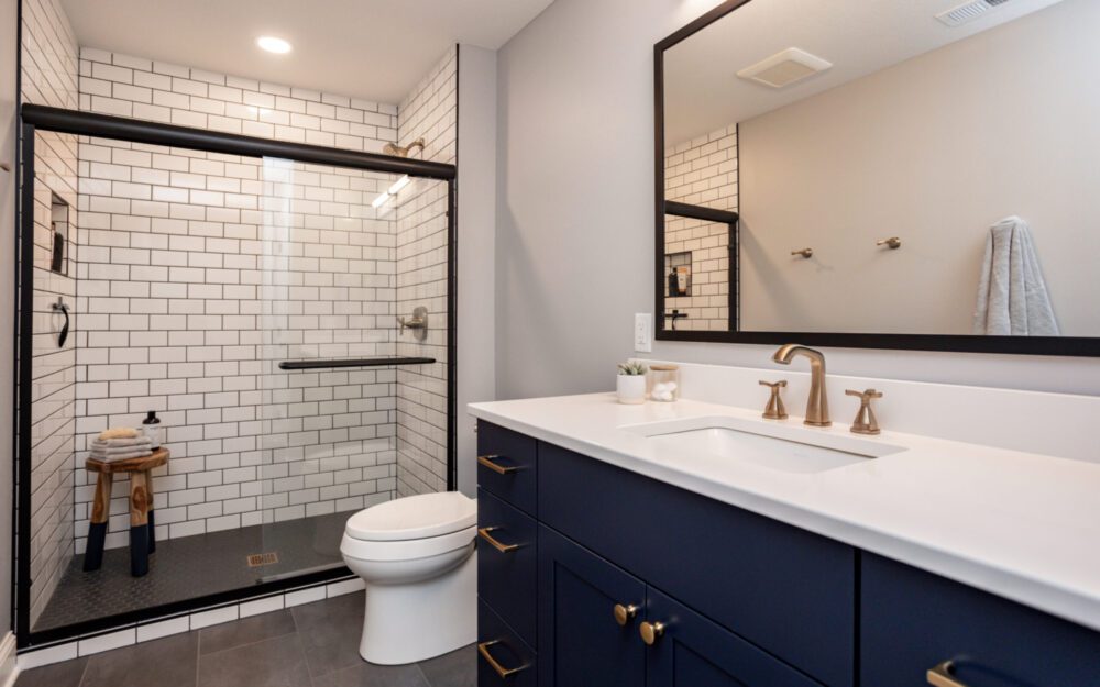 A bathroom with white tiles and dark blue cabinet