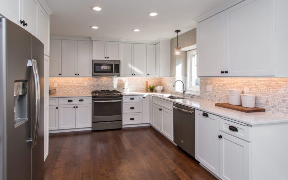 A white kitchen with grey colored appliances  