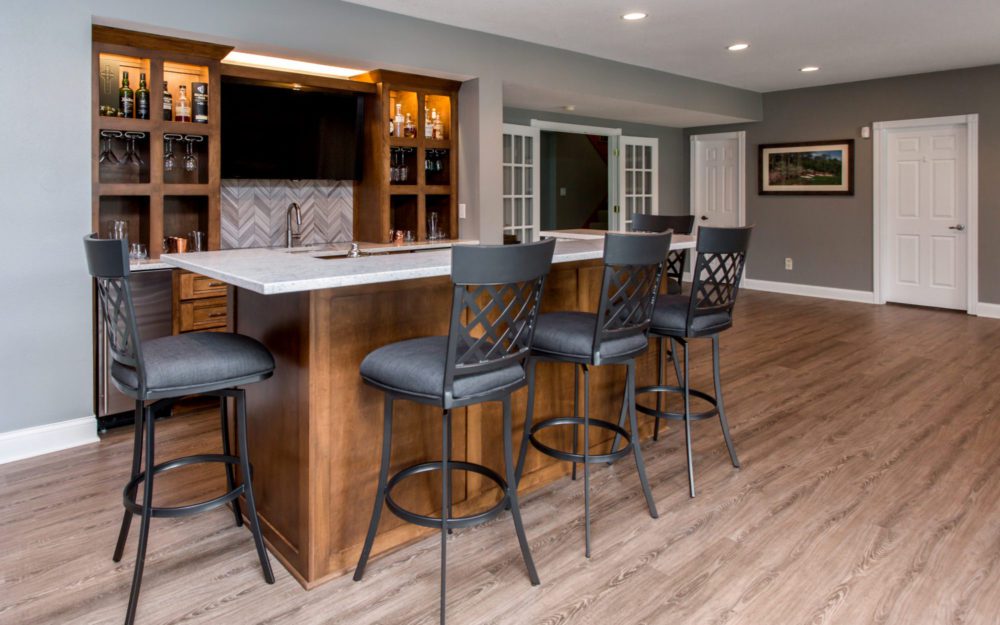 A liquor bar area with black chairs and wooden cabinetry