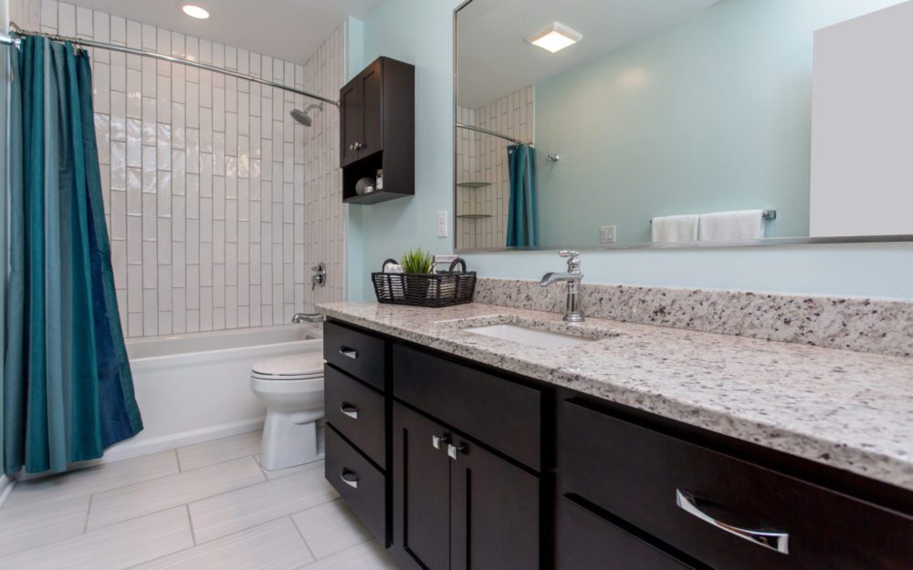 A light blue bathroom with dark brown cabinetry