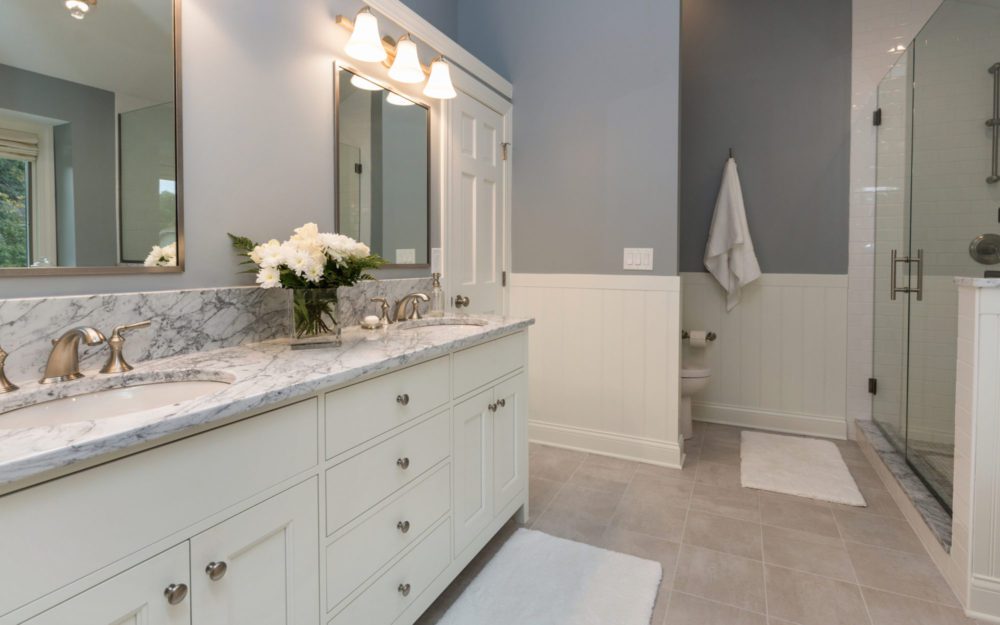 A grey and white bathroom with counterops and mirrors