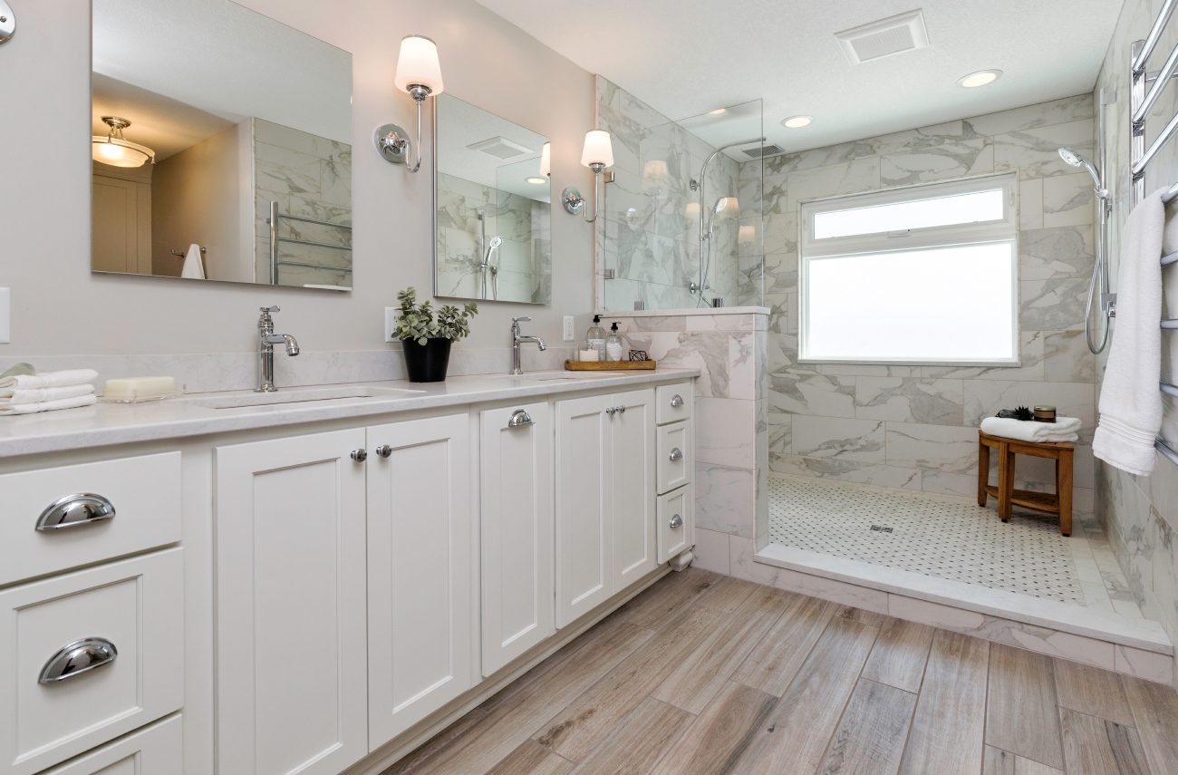 A white bathroom with two mirrors and a large shower area