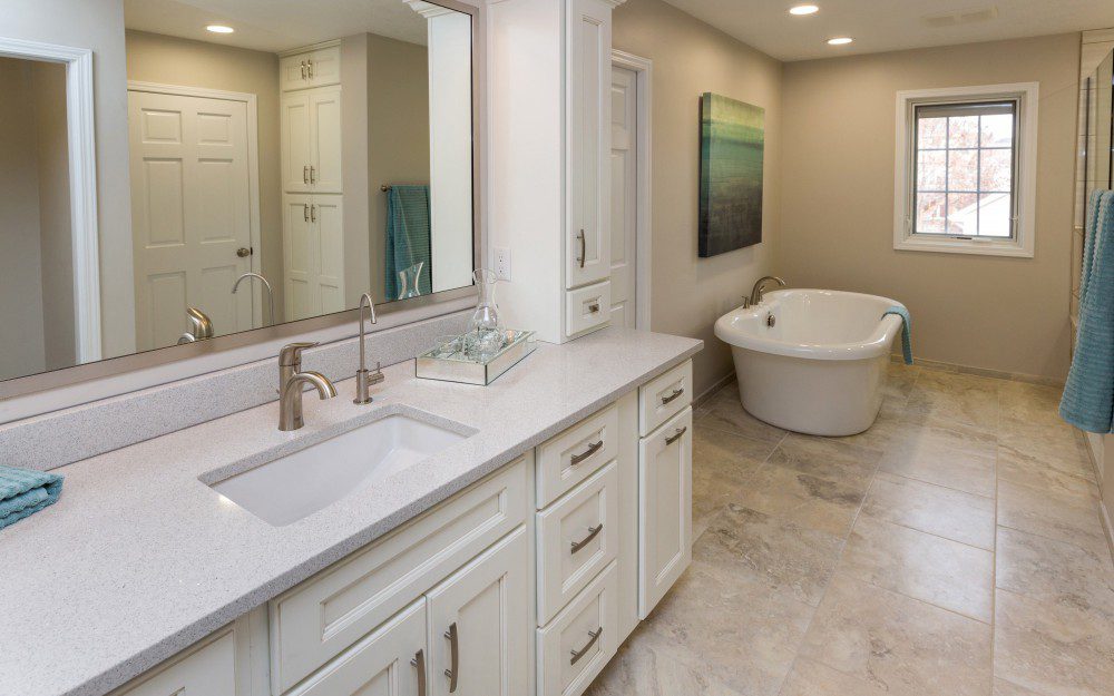A bathroom with a long white countertop with a large mirror